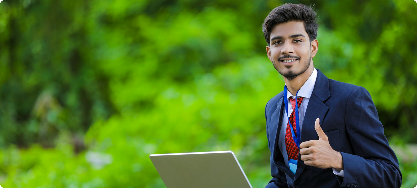Student in a suit giving a thumbs-up with laptop